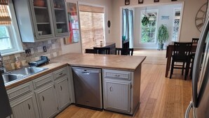 Une cuisine dotée d’un îlot central, d’un plancher en bois et donnant sur l’espace repas.