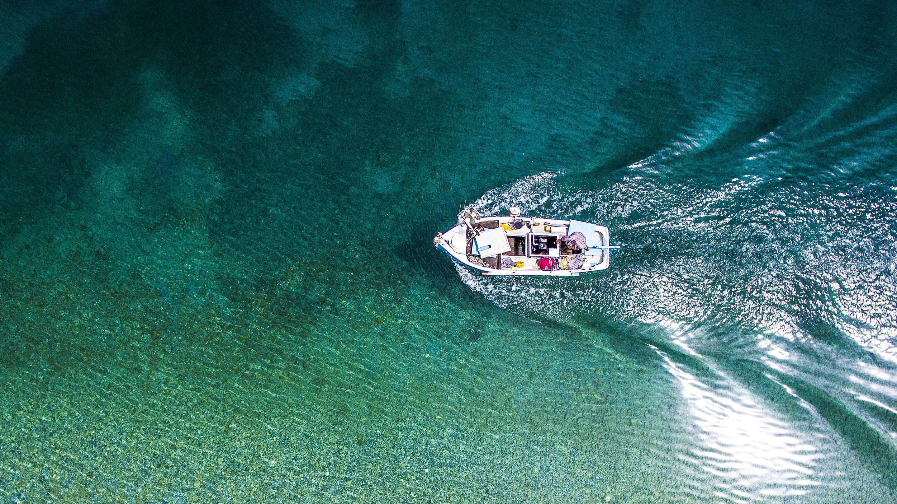 Vista aérea de un barco en aguas turquesas cristalinas.