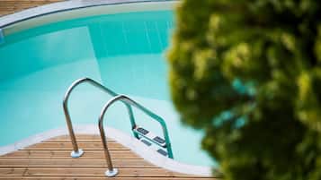 En swimmingpool med træterrasse og metalgelændere.