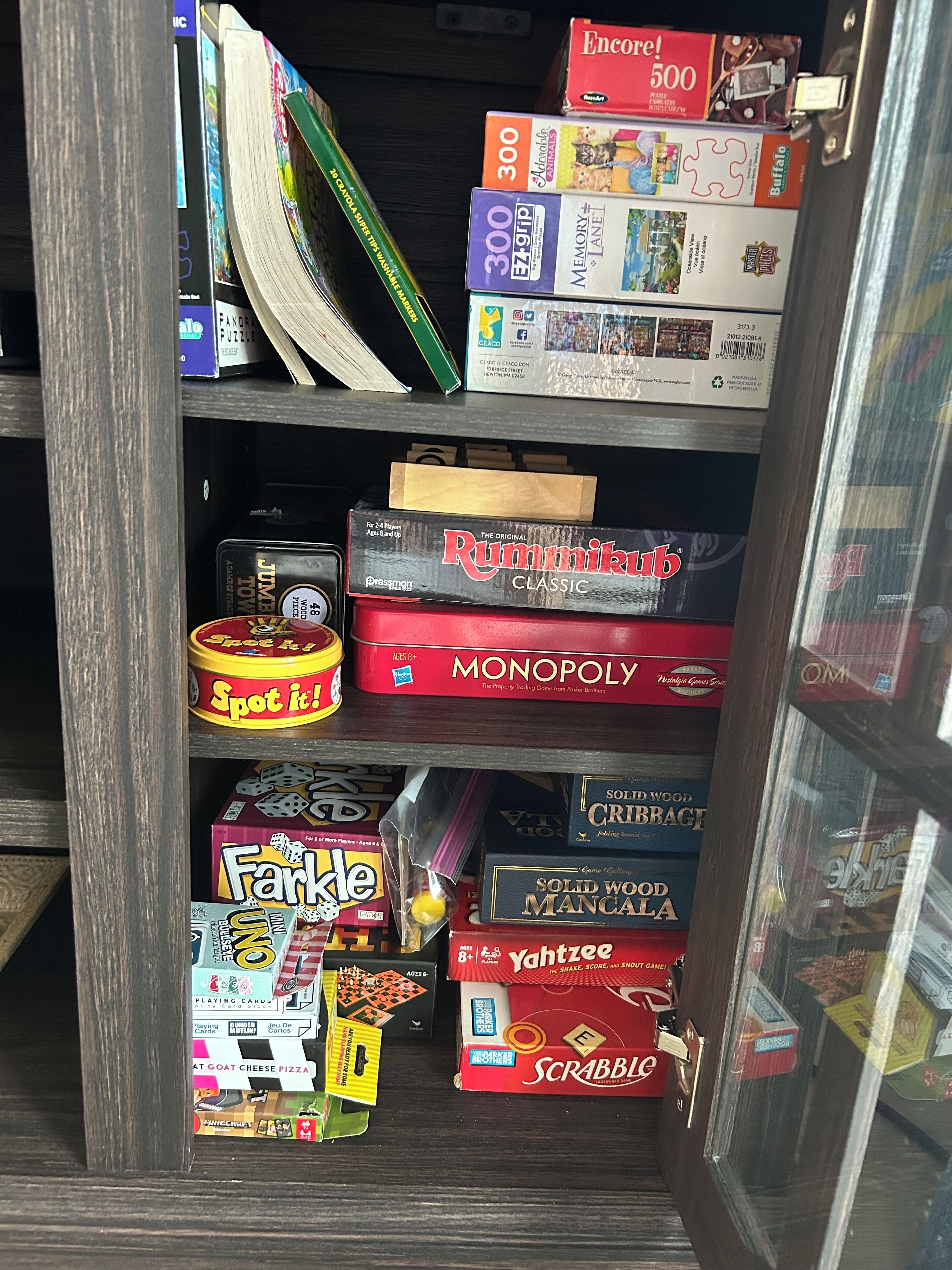A shelf with various board games including Monopoly, Scrabble, and others.