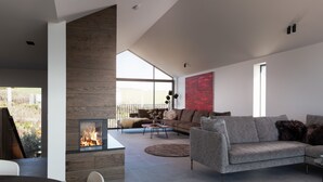 A modern living room with a fireplace, a grey sofa, and a dining area.