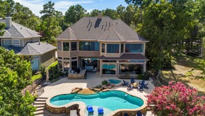 A two-story house with a large backyard featuring a swimming pool, outdoor seating, and a fire pit. - Waterfront home, 6 bedrooms private pool and dock on Lake Conroe (Montgomery)