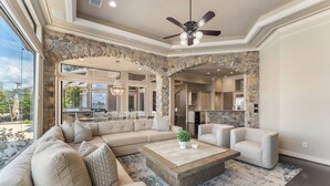 A spacious living room with a sectional sofa, a coffee table, and a stone archway leading to the kitchen. - Waterfront home, 6 bedrooms private pool and dock on Lake Conroe (Montgomery)