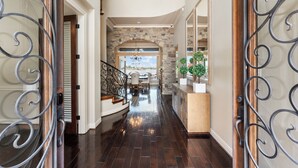A spacious hallway with a stone archway, wooden flooring, and a chandelier. - Waterfront home, 6 bedrooms private pool and dock on Lake Conroe (Montgomery)