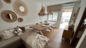 Een moderne woonkamer met een bank, een eettafel en hangende rieten lampen.