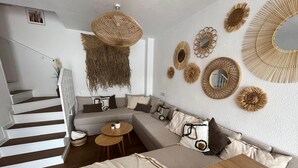 Een moderne woonkamer met een hoekbank, een houten salontafel en een trap naar een hoger niveau.