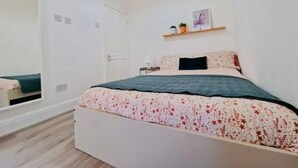Un dormitorio con cama, armario, puerta y estante con una planta.