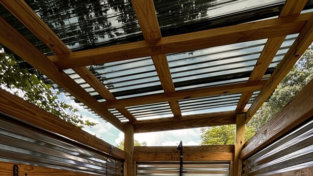 A wooden structure with a metal roof and wooden flooring.