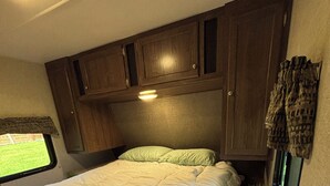 A bedroom with a bed, a window, and wooden cabinets.