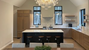 A spacious kitchen with a large island, wooden cabinets, and a unique chandelier. - Brand NEW MINT Windham 5BR/4.5BA home on 5 acre, wooded hilltop. (Windham)
