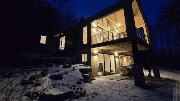 A modern two-story house with large windows and a balcony, surrounded by snow. - Brand NEW MINT Windham 5BR/4.5BA home on 5 acre, wooded hilltop. (Windham)
