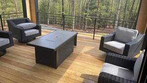 A deck with wicker furniture and a black table, overlooking a forest. - Brand NEW MINT Windham 5BR/4.5BA home on 5 acre, wooded hilltop. (Windham)