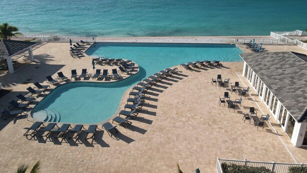 A pool area with sun loungers and a view of the ocean. - "Serenity" at the Infiniti Pool - Oceanview 2/2 at Resorts World Bimini Bay (Bimini)