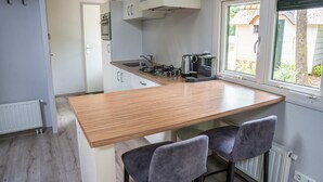 Una cocina compacta con encimera de madera, dos sillas, una estufa a gas y ventana con vistas al exterior.