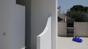 Un edificio moderno con fachada blanca, un patio empedrado y un objeto azul en el suelo.