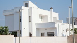 Un edificio moderno blanco con techo plano, una chimenea y un pequeño balcón.