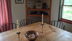 Una mesa de madera para comer con dos velas, un salero y pimentero, y un cuenco decorativo.