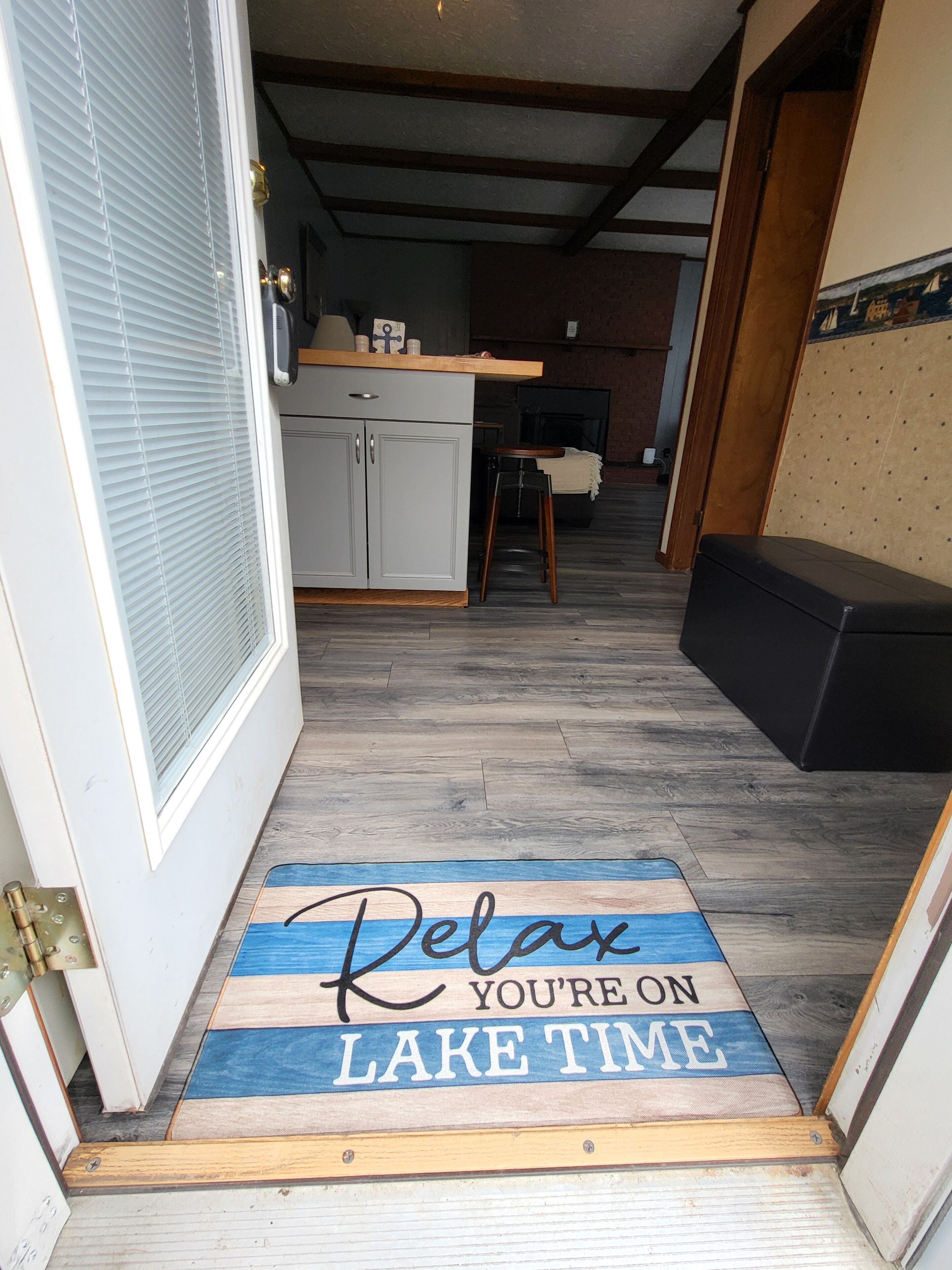 A wooden door with a mat that reads "Relax, you're on lake time."