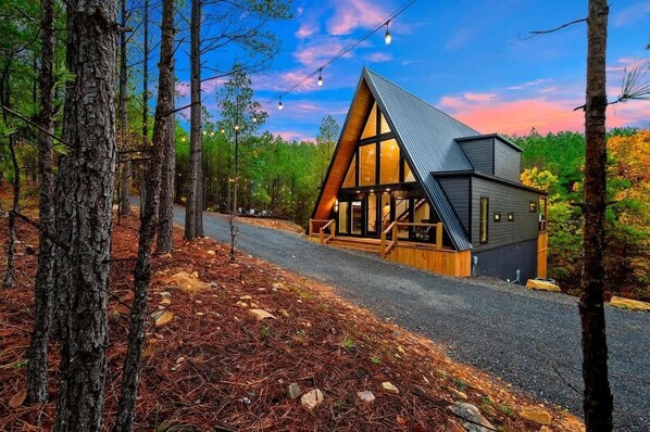 Eine Hütte mit geneigtem Dach, großen Fenstern und einer Holzterrasse.