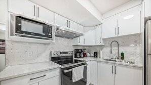 A modern kitchen with white cabinets, stainless steel appliances, and a marble backsplash. - Rome Sweet Home 2. Private Guest Suite in a quiet, family-friendly neighborhood. (Calgary)