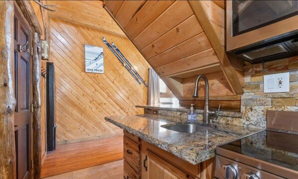A kitchen with wooden walls, a granite countertop, a stainless steel sink, and a built-in oven. - Heavenly Ski Retreat (Stateline)