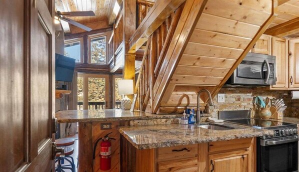 A kitchen with wooden cabinets, granite countertops, a microwave, and a stove. - Heavenly Ski Retreat (Stateline)