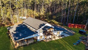 A two-story house with a large garage, surrounded by a forest. - Charming 2-bedroom barn with WiFi, AC in awesome Midland (Midland)