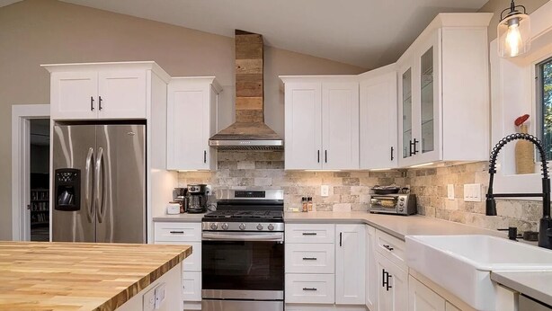 A modern kitchen with white cabinets, stainless steel appliances, a wooden backsplash, and a built-in oven. - Charming 2-bedroom barn with WiFi, AC in awesome Midland (Midland)