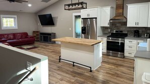 A modern kitchen with white cabinets, a stainless steel refrigerator, and a wood-burning stove. - Charming 2-bedroom barn with WiFi, AC in awesome Midland (Midland)