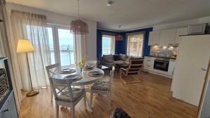 A modern kitchen with white cabinets, a microwave, and a dining area with a round table and chairs. - Hausboot in Barth am Barther Bodden (Barth)