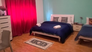 Un dormitorio con cama, dos mesitas de noche, una silla, un aparador y una alfombra.