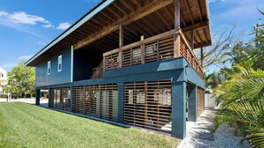 A two-story house with a balcony, a fenced yard, and a clear sky. - Relax & Recharge at 3BR Indian Rocks Beach Family Retreat - Short walk to beach (Indian Rocks Beach)