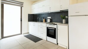 A modern kitchen with white cabinets, a black countertop, a built-in oven, and a refrigerator. - Elysee apartment 7 (Athens)