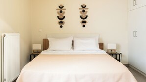 A neatly made bed with white linens, two bedside tables with lamps, and a wall-mounted decorative piece. - Elysee apartment 7 (Athens)