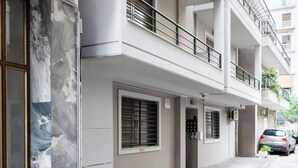 A multi-story residential building with a clean, modern design, featuring balconies and large windows. - Elysee apartment 7 (Athens)