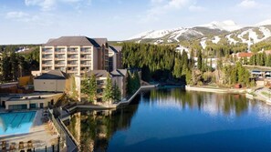 Un hotel con piscina, vistas a la montaña y un área boscosa.