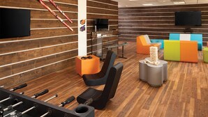A room with a foosball table, a TV, and colorful seating.