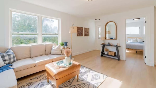 A modern living room with a beige sofa, a wooden coffee table, and a patterned rug. - Charming 3BR Beach House with BBQ in Grand Bend (Grand Bend)