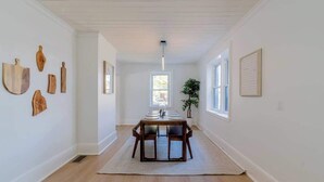 A dining area with a wooden table and chairs, a white rug, and a plant. - Charming 3BR Beach House with BBQ in Grand Bend (Grand Bend)