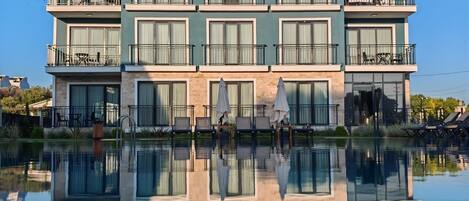 Un hotel de varios pisos con balcones y una piscina al frente.