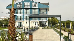 A modern hotel with a blue facade, multiple balconies, and outdoor seating areas. - GRAPE HOTEL (Ezine)