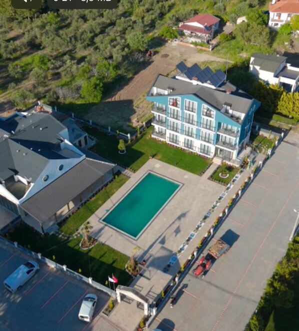 An aerial view of a hotel with a swimming pool, multiple buildings, and a parking lot. - GRAPE HOTEL (Ezine)