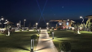 A nighttime view of a well-lit outdoor area with a paved walkway leading to a building. - GRAPE HOTEL (Ezine)