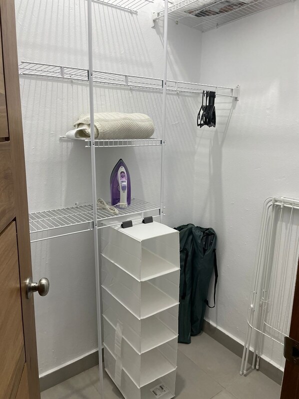 A storage closet with shelves, a hanging rack, and a radiator.