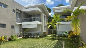 A modern apartment complex with multiple balconies, a well-maintained lawn, and tropical plants.