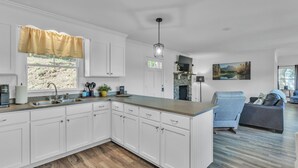 A modern kitchen with white cabinetry, a granite countertop, and a built-in island.