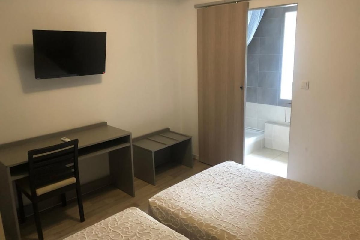 Un dormitorio con cama, escritorio, silla y televisor.