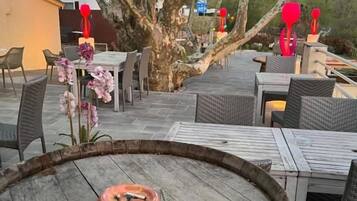 An outdoor patio area with tables and chairs, a wooden barrel, and a tree.