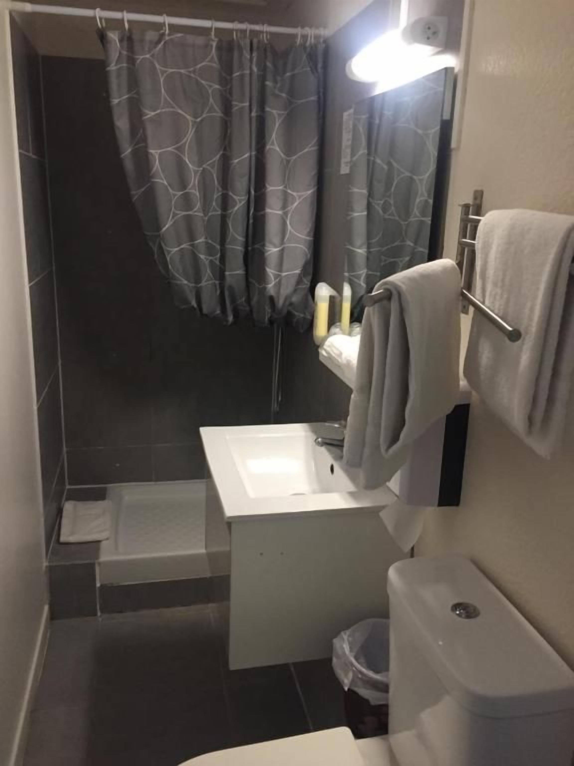 A bathroom with a white sink, a toilet, a shower curtain, and a towel rack.