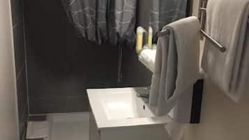 A bathroom with a white sink, a toilet, a shower curtain, and a towel rack.